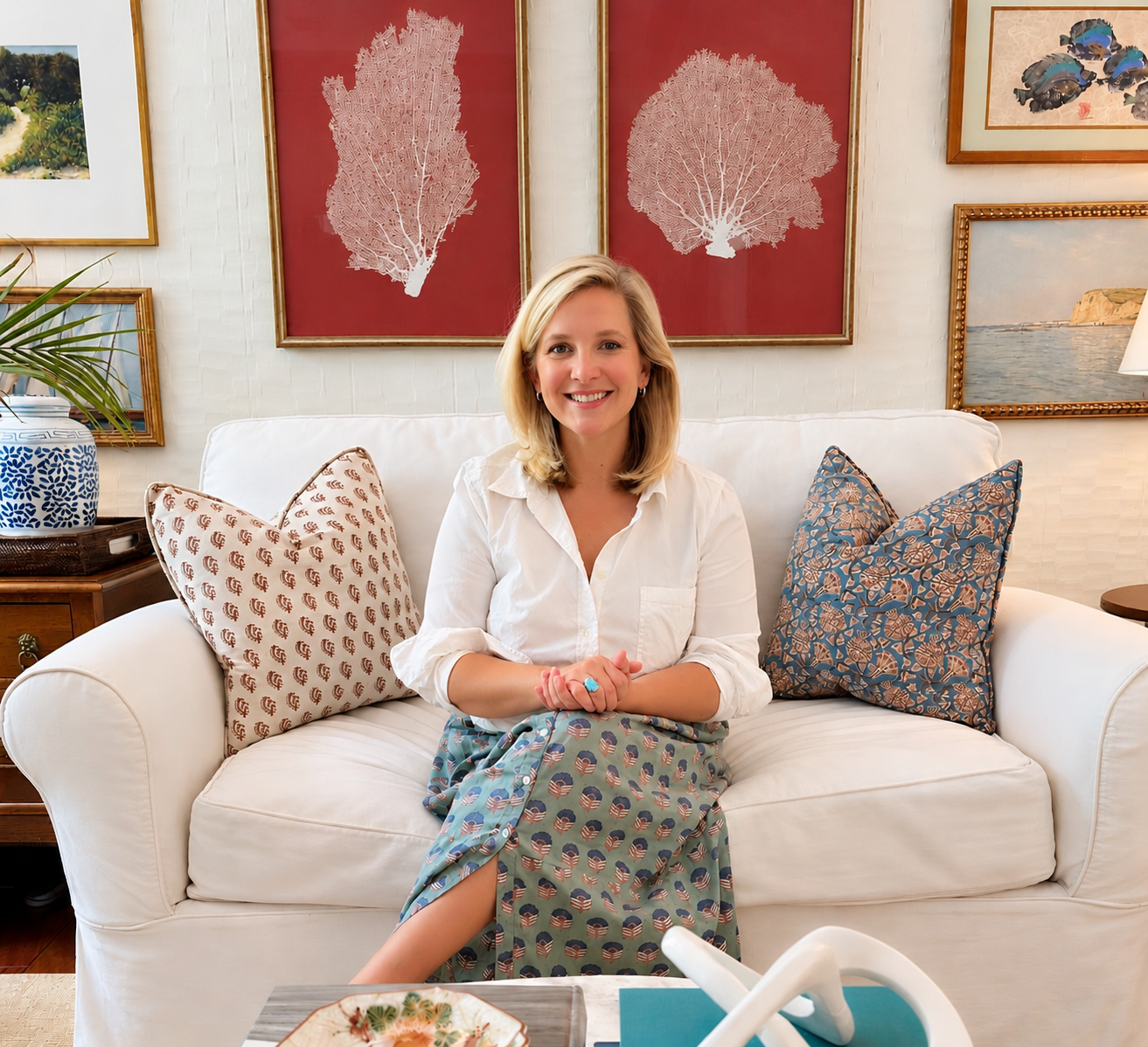 Stefanie Friedland seated on a white sofa with patterned pillows and layered artwork